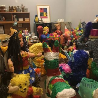 Room filled with many colorful pinatas of people and animals.