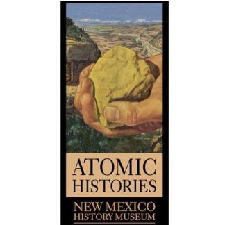 Atomic Histories. New Mexico History Museum. Large hand holding rock with desert scenery and building in background.